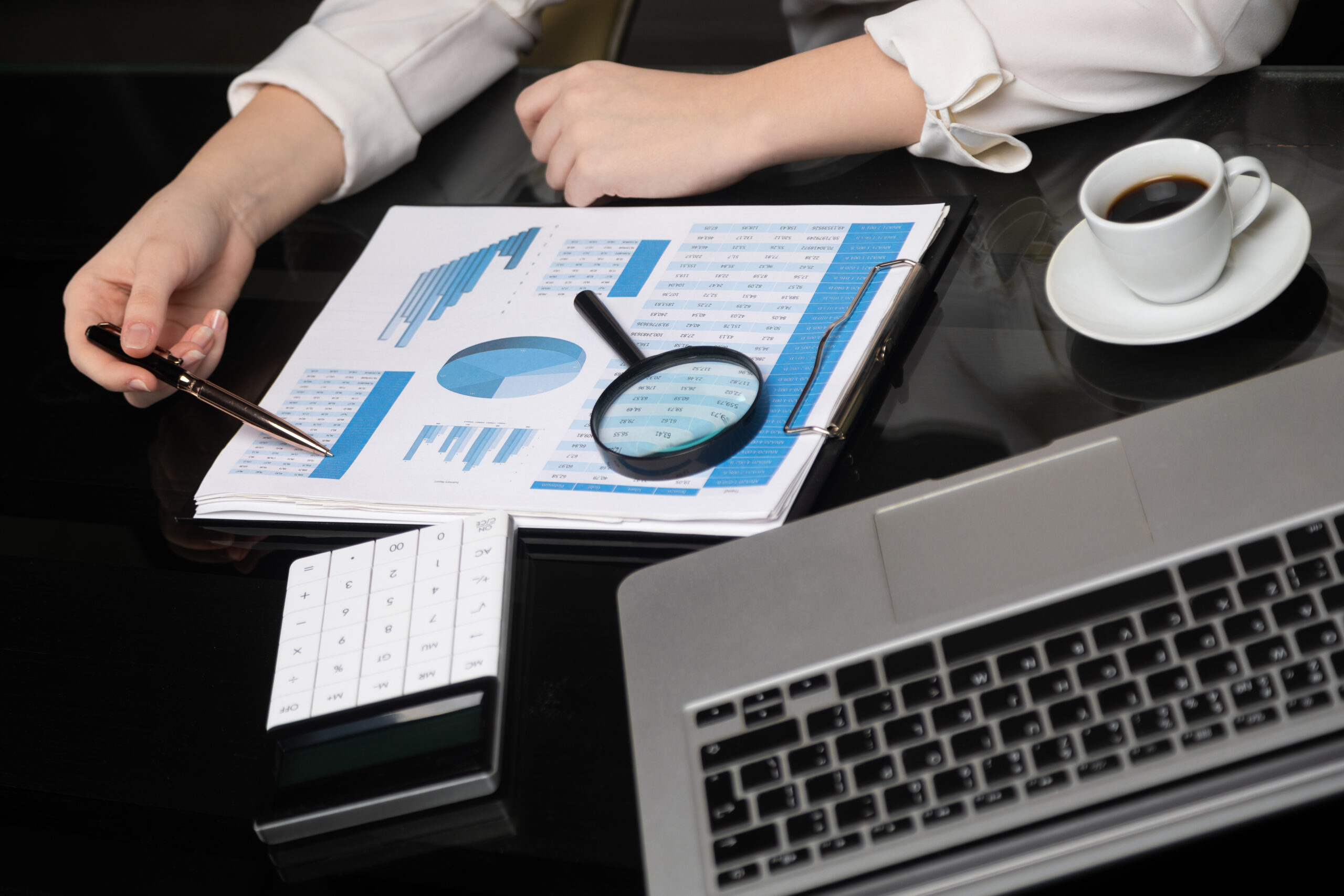 Businesswoman with coffee and pen points to graph